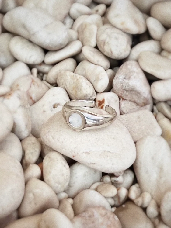 Srebrny sygnet z polskim opalem na tle jasnych kamieni.