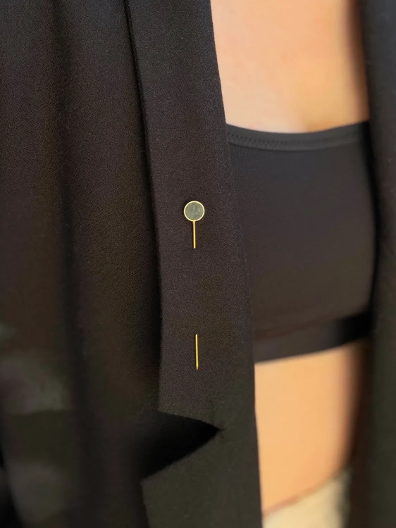 Złota szpilka ozdobiona ciemnozielonym kamieniem naturalnym.