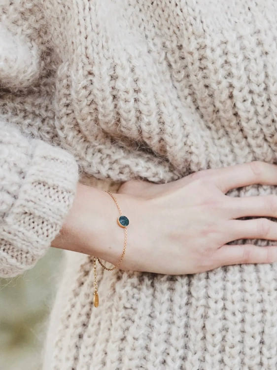 Modelka w dzianinowym swetrze prezentuje bransoletkę z nefrytem na nadgarstku w codziennej stylizacji.